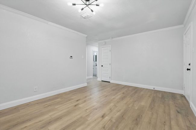 Spare room featuring crown molding, light wood finished floors, a chandelier, and baseboards | Image 5