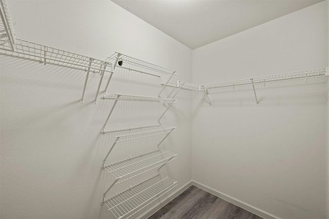 Walk-in master closet with built-in shelves, ideal for storing shoes, accessories, or bulky sweaters that don't hang well. Thoughtful design offers great organization, keeping clothing and personal items neatly arranged and easily accessible. | Image 24