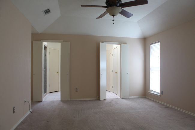 Unfurnished bedroom with light carpet, multiple windows, lofted ceiling, baseboards, and a ceiling fan | Image 14