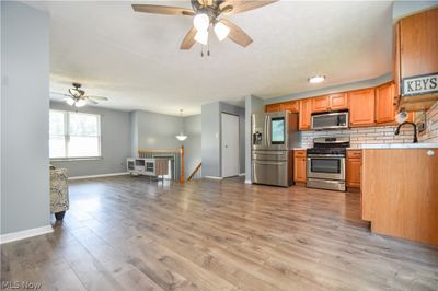 Kitchen featuring ceiling fan, tasteful backsplash, light wood-type flooring, and stainless steel appliances | Image 3