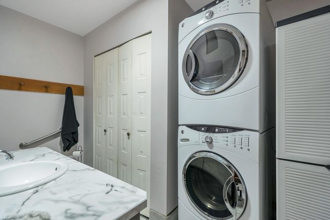 Washroom featuring a sink, stacked washer / drying machine, and laundry area | Image 18