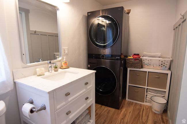 Washroom featuring stacked washing machine and dryer and light wood-type flooring | Image 22
