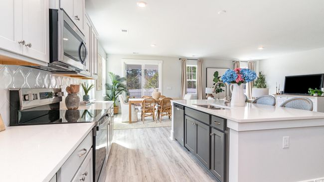 Kitchen featuring stainless steel appliances, a sink, light wood-style floors, light countertops, and an island with sink | Image 12