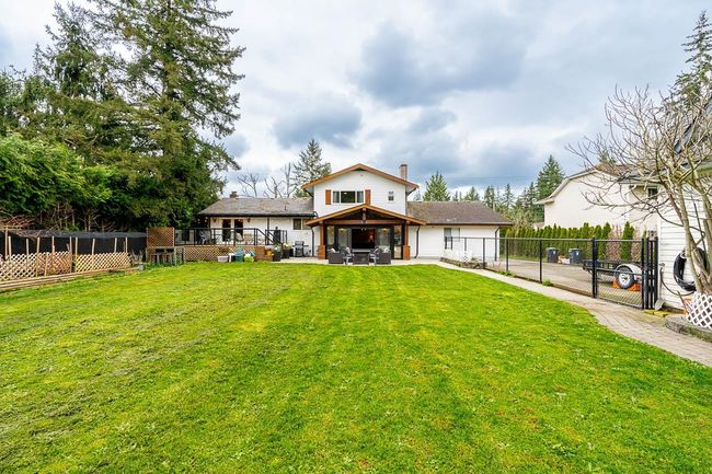 Rear view of property featuring a patio area, a gazebo, a chimney, fence, and a lawn | Image 33