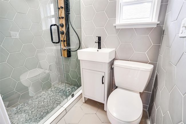 Bathroom featuring tile walls, toilet, a shower stall, tile patterned floors, and vanity | Image 12