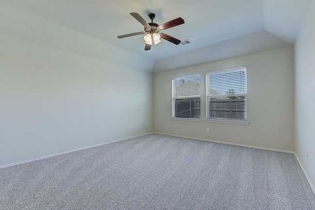 Carpeted empty room with a ceiling fan, baseboards, and lofted ceiling | Image 10