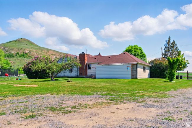 Rear view of house featuring a trampoline, a lawn, a mountain view, and a chimney | Image 26