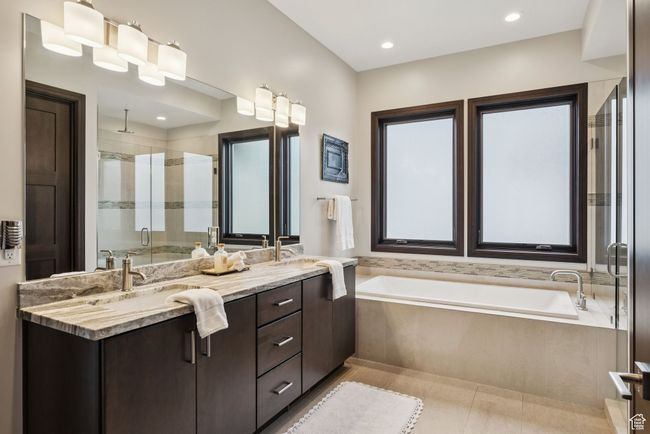 Bathroom featuring a stall shower, double vanity, a bath, tile patterned flooring, and recessed lighting | Image 36
