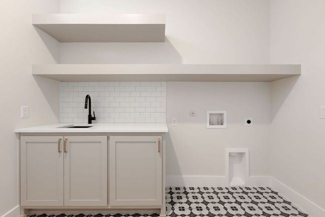 Clothes washing area featuring hookup for a washing machine, cabinet space, electric dryer hookup, a sink, and hookup for a gas dryer | Image 12