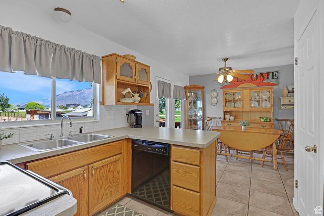 Kitchen featuring black dishwasher, a sink, electric range, a peninsula, and light countertops | Image 11