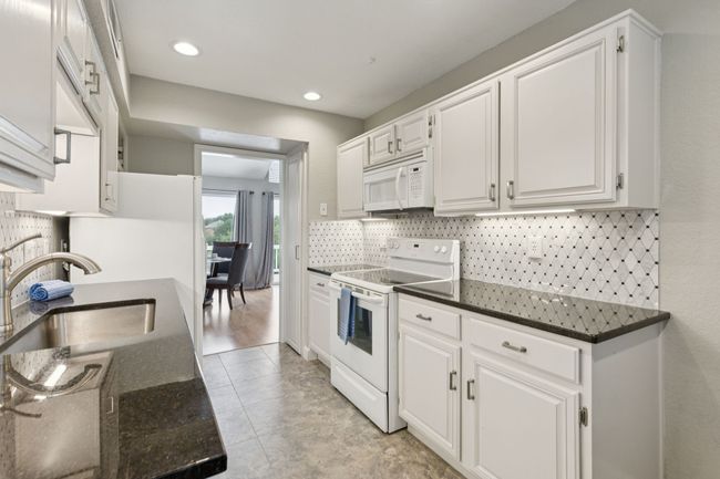 Kitchen featuring white appliances, a sink, white cabinetry, backsplash, and recessed lighting | Image 13