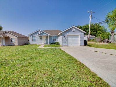 Ranch-style house with a front lawn and a garage | Image 1