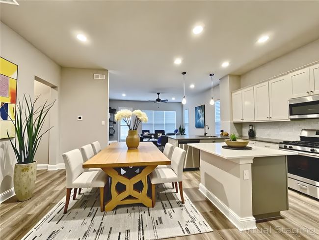Kitchen featuring stainless steel appliances, a sink, light wood-type flooring, white cabinets, and backsplash | Image 4