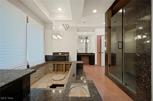 Bathroom featuring two vanities, a shower stall, tile patterned floors, a raised ceiling, and a bath | Image 11