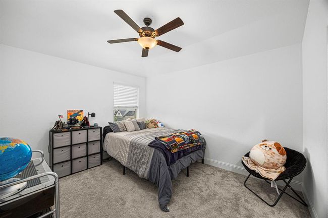 Secondary bedroom with ceiling fan, neutral walls and large window. | Image 42