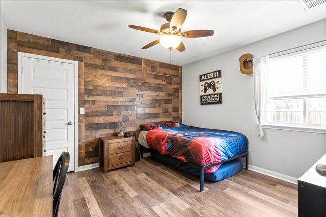 Bedroom with wood walls, wood laminate floors, baseboards, and ceiling fan | Image 23