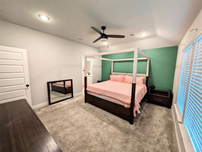 Carpeted bedroom featuring visible vents, baseboards, a ceiling fan, and lofted ceiling | Image 4