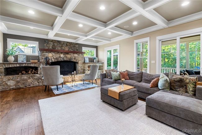 Living area with a stone fireplace, wood finished floors, coffered ceiling, beamed ceiling, and healthy amount of natural light | Image 18