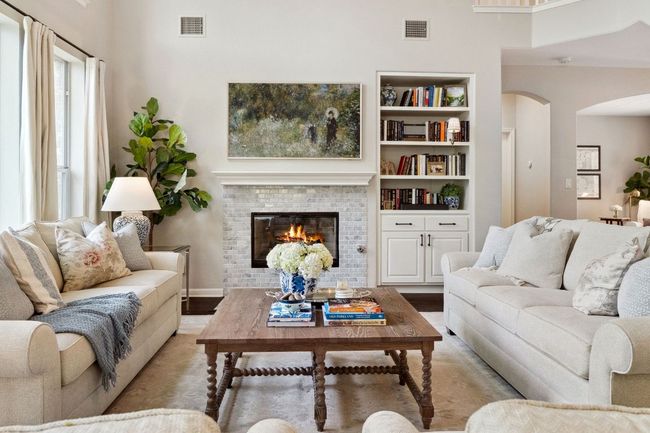 A cozy gas log fireplace sets a relaxing atmosphere, framed in brick with a wood mantel. | Image 6