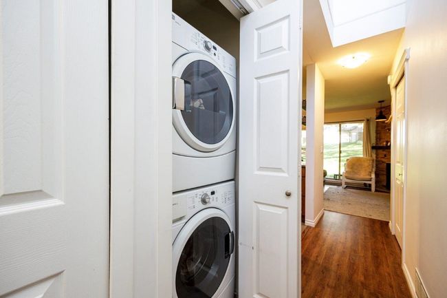 Laundry room featuring laundry area, stacked washer / drying machine, and dark wood-type flooring | Image 8