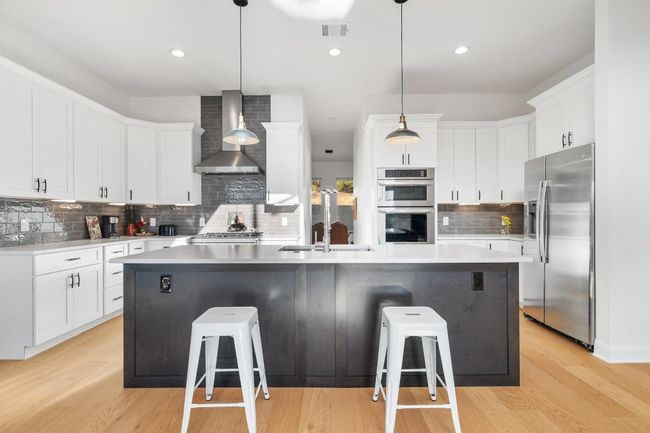 stainless steel appliances, a kitchen island, quartz countertops, and an Instant hot water system. | Image 8