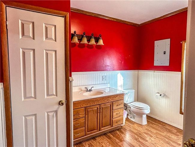 Bathroom with electric panel, a wainscoted wall, ornamental molding, wood finished floors, and vanity | Image 13
