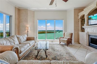 Living room featuring crown molding, ceiling fan, a large fireplace, and a water view | Image 3