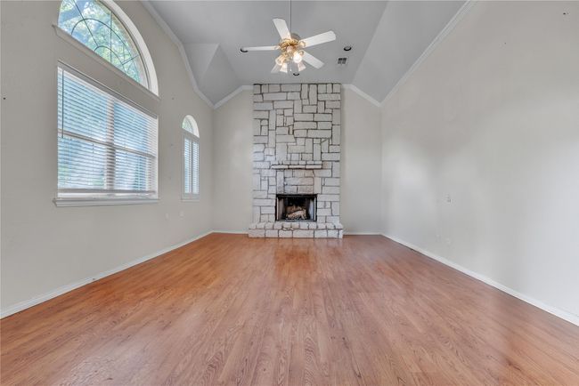 Unfurnished living room featuring plenty of natural light, a ceiling fan, ornamental molding, a fireplace, and light wood-style floors | Image 10