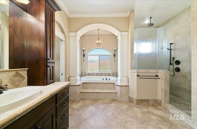 Full bath featuring a bath, a walk in shower, crown molding, vanity, and ornate columns | Image 20