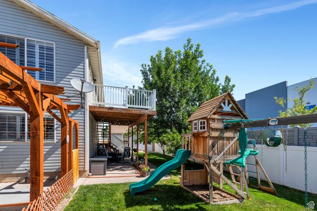 View of jungle gym featuring a fenced backyard, a patio, and a deck | Image 22