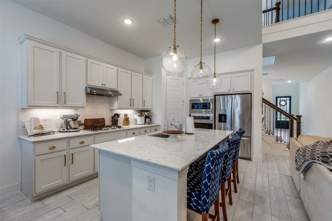 Kitchen featuring under cabinet range hood, stainless steel appliances, a sink, tasteful backsplash, and wood finish floors | Image 8