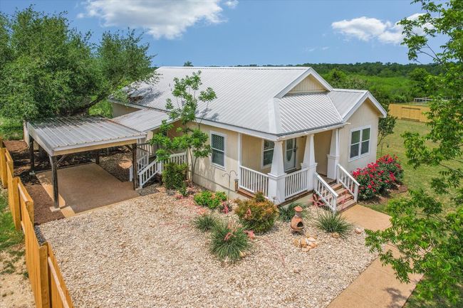 View of front of house with covered porch, metal roof, a carport, and gravel driveway | Image 6