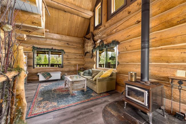 Living room with healthy amount of natural light, a wood stove, rustic walls, wooden ceiling, and wood finished floors | Image 10