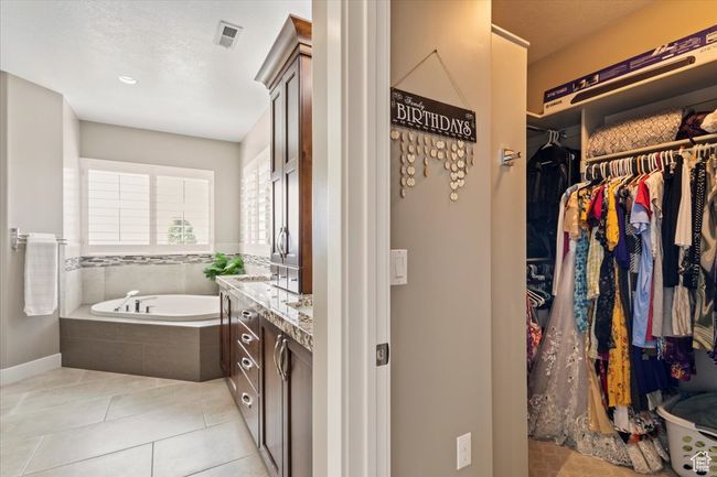Bathroom with vanity, a garden tub, a walk in closet, tile patterned floors, and baseboards | Image 37