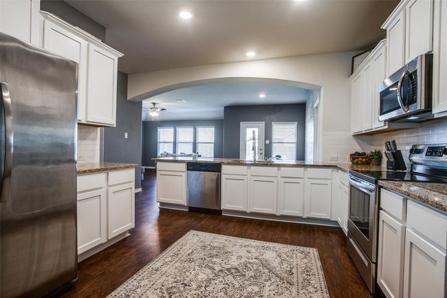 Kitchen with appliances with stainless steel finishes, tasteful backsplash, dark hardwood / wood-style floors, and ceiling fan | Image 8