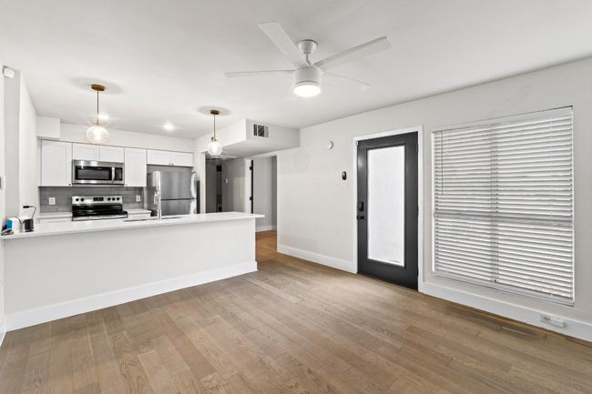 Kitchen with appliances with stainless steel finishes, a peninsula, tasteful backsplash, baseboards, and a ceiling fan | Image 10