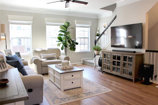 Living room with stairs, light wood-type flooring, ceiling fan, and ornamental molding | Image 5