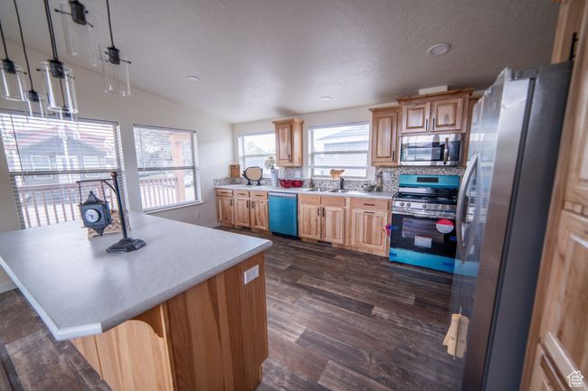 Kitchen with dark wood-style floors, a sink, vaulted ceiling, light countertops, and appliances with stainless steel finishes | Image 6