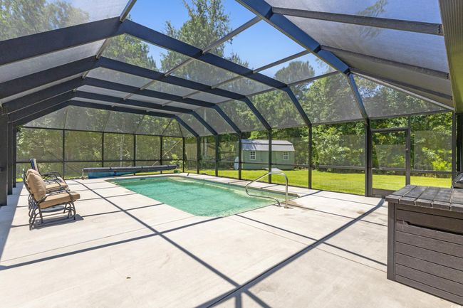 Swimming pool featuring a patio, a yard, a shed, and glass enclosure | Image 33