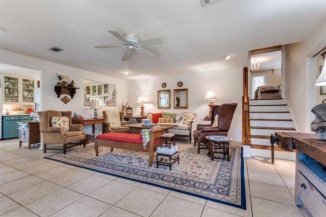 Living area with ceiling fan, light tile patterned floors, and stairway | Image 11