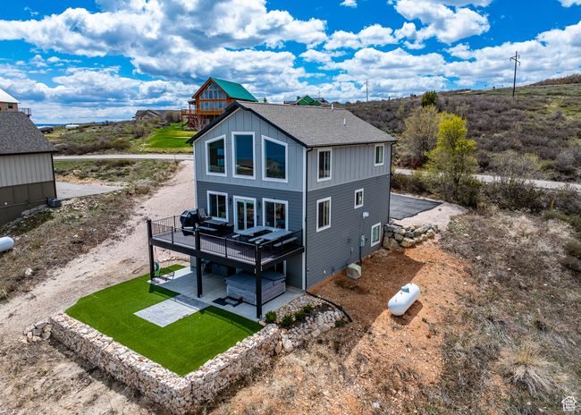 Rear view of house featuring a deck, roof with shingles, a patio area, board and batten siding, and a yard | Image 9