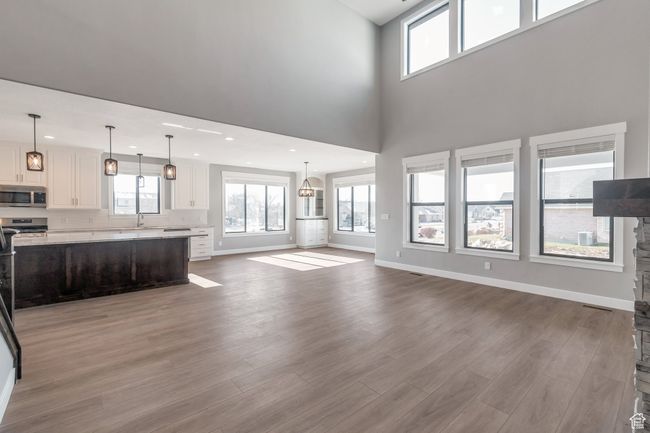 Unfurnished living room featuring wood finished floors, healthy amount of natural light, recessed lighting, and a high ceiling | Image 16