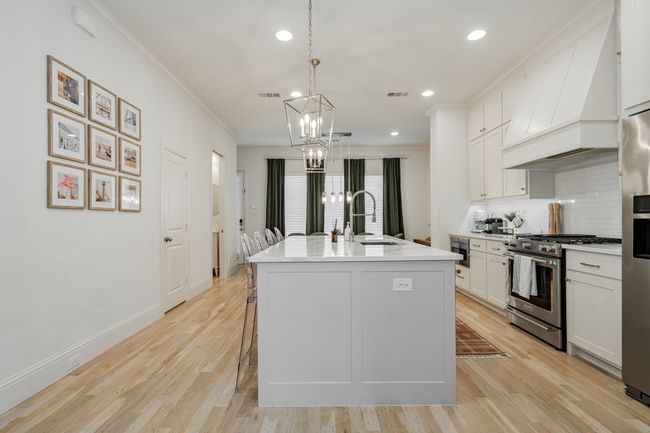Kitchen with custom range hood, an inviting chandelier, gas stove, backsplash, and a sink | Image 8