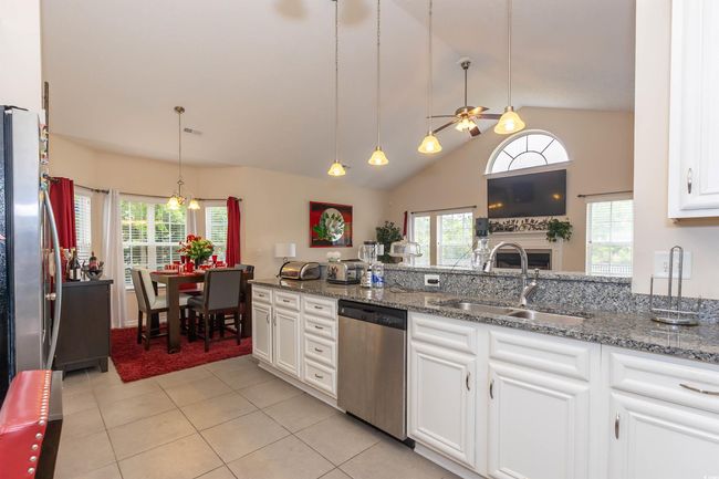 Kitchen with a ceiling fan, dark stone countertops, a sink, white cabinets, and appliances with stainless steel finishes | Image 10