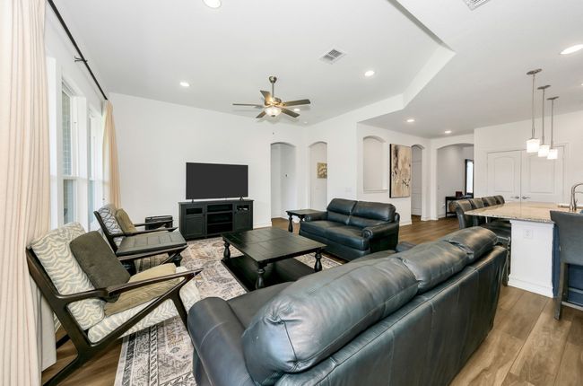 Living room with wood finished floors, ceiling fan, arched walkways, visible vents, and recessed lighting | Image 11