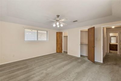 Unfurnished bedroom featuring a closet, lofted ceiling, ceiling fan, a walk in closet, and light colored carpet | Image 3