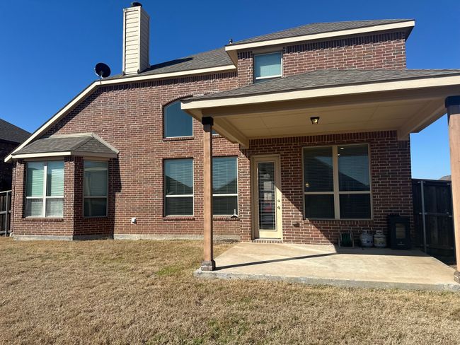 Back of property featuring brick siding, a shingled roof, a yard, a chimney, and a patio area | Image 28