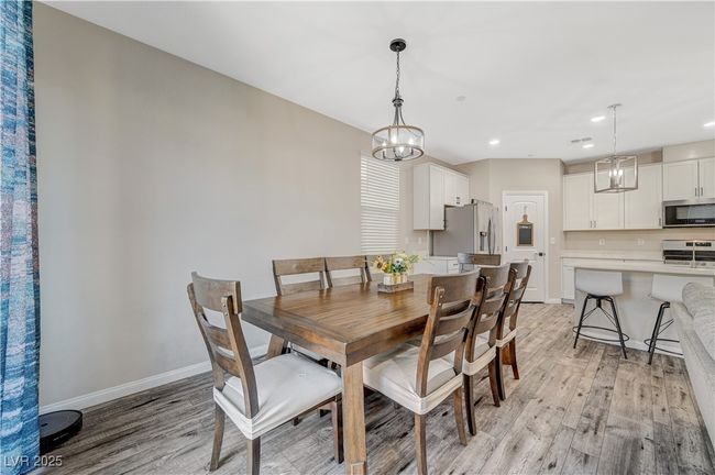 Dining room with light wood finished floors, recessed lighting, baseboards, and a chandelier | Image 16