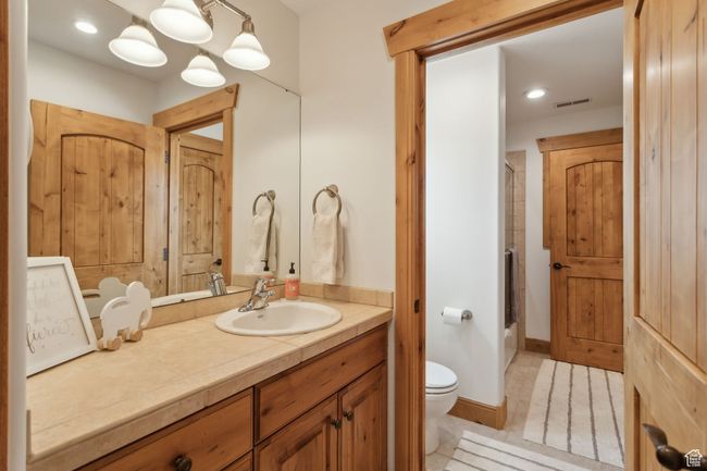 Full bath featuring toilet, vanity, shower / bath combination with glass door, recessed lighting, and tile patterned flooring | Image 33