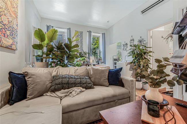 Living area featuring a wall mounted air conditioner and wood finished floors | Image 7